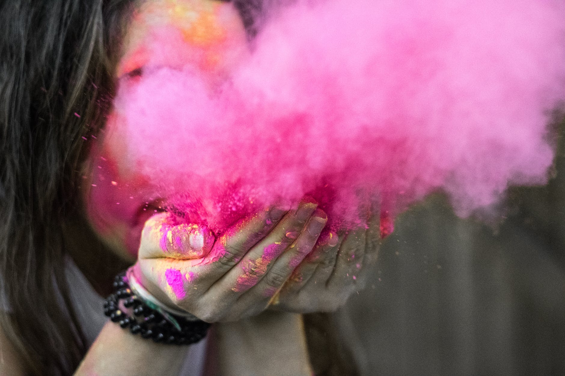 shallow focus photograph of woman blowing pink powder